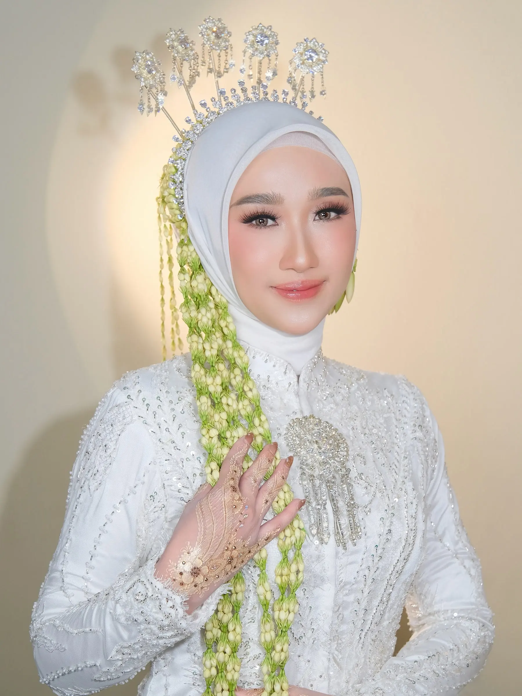 Riasan akad: pengantin berhijab putih dengan siger perak, ronce melati, dan henna emas di tangan