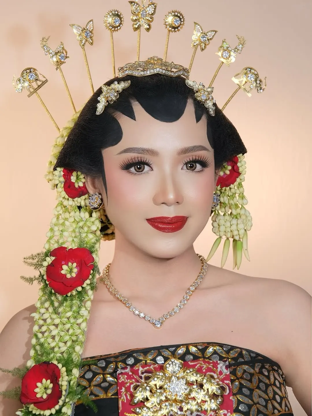Tampilan dekat riasan pengantin paes dengan bibir merah, cunduk mentul emas, dan ronce melati