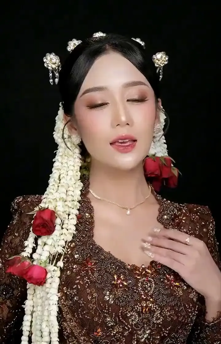 Riasan pengantin Pungky Olivia Makeup dengan untaian melati dan mawar merah, berlatar gelap