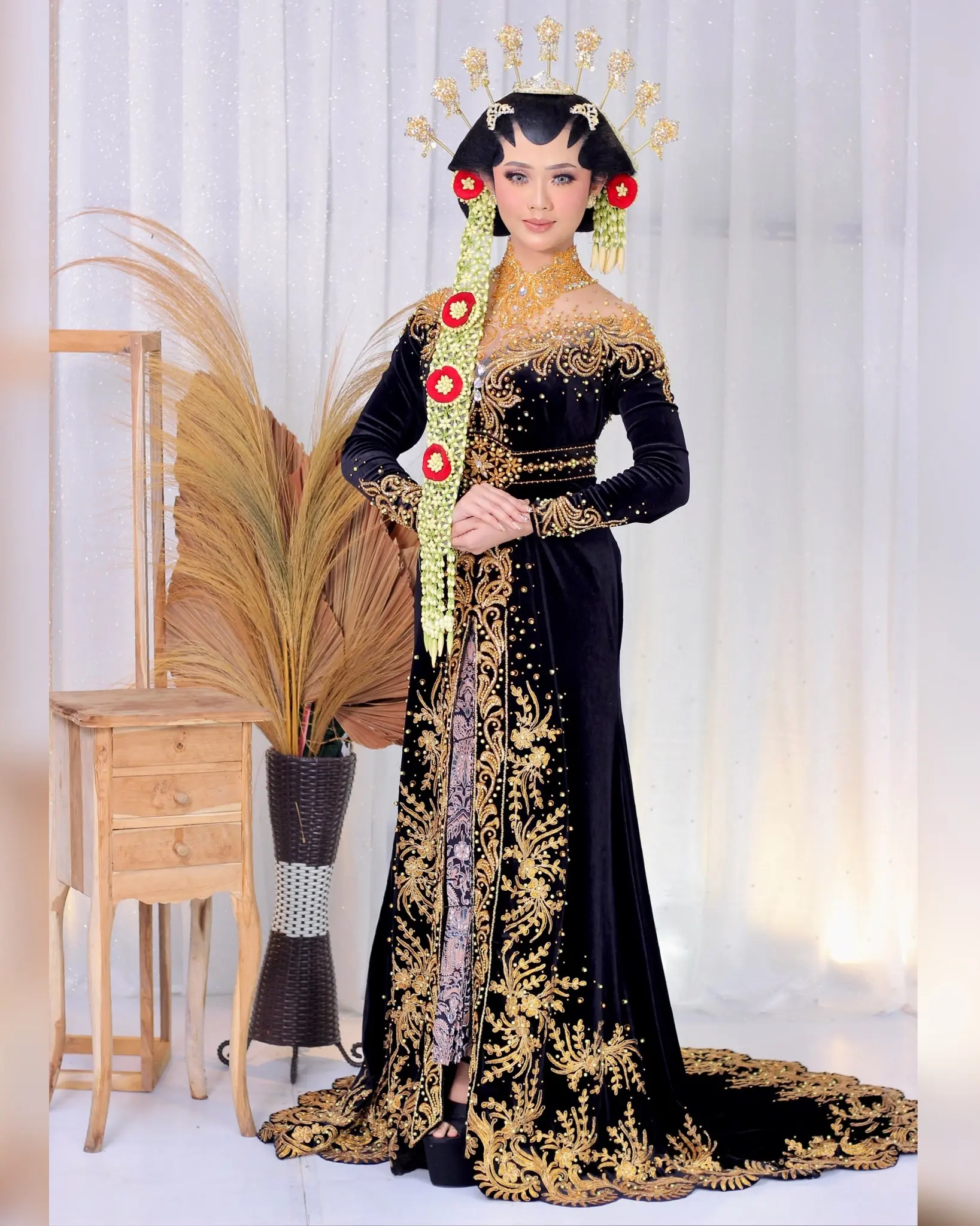 Pengantin paes berdiri memakai kebaya beludru hitam panjang bersulam emas