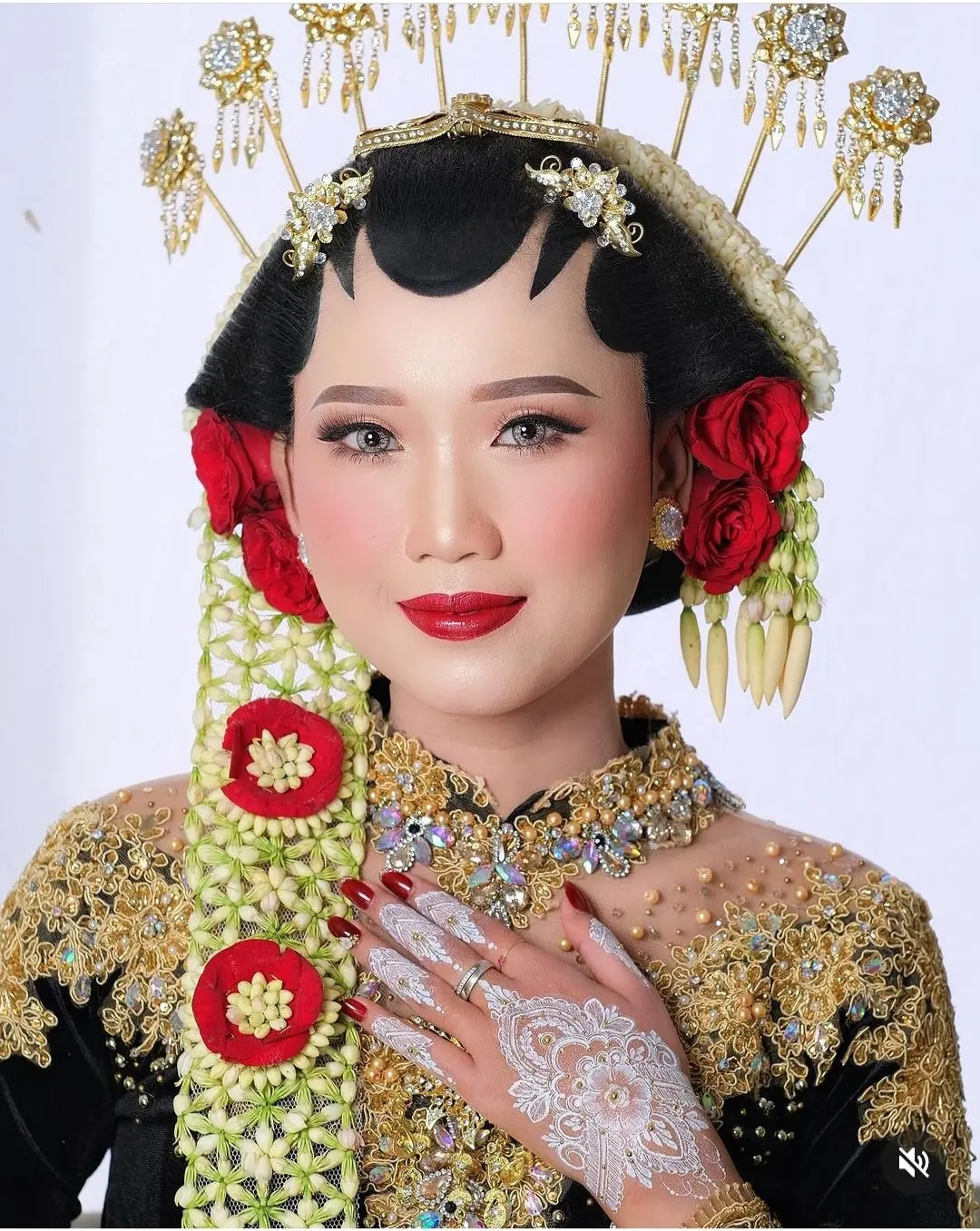Riasan pengantin paes dengan mawar merah di sanggul, ronce melati, dan henna putih di tangan