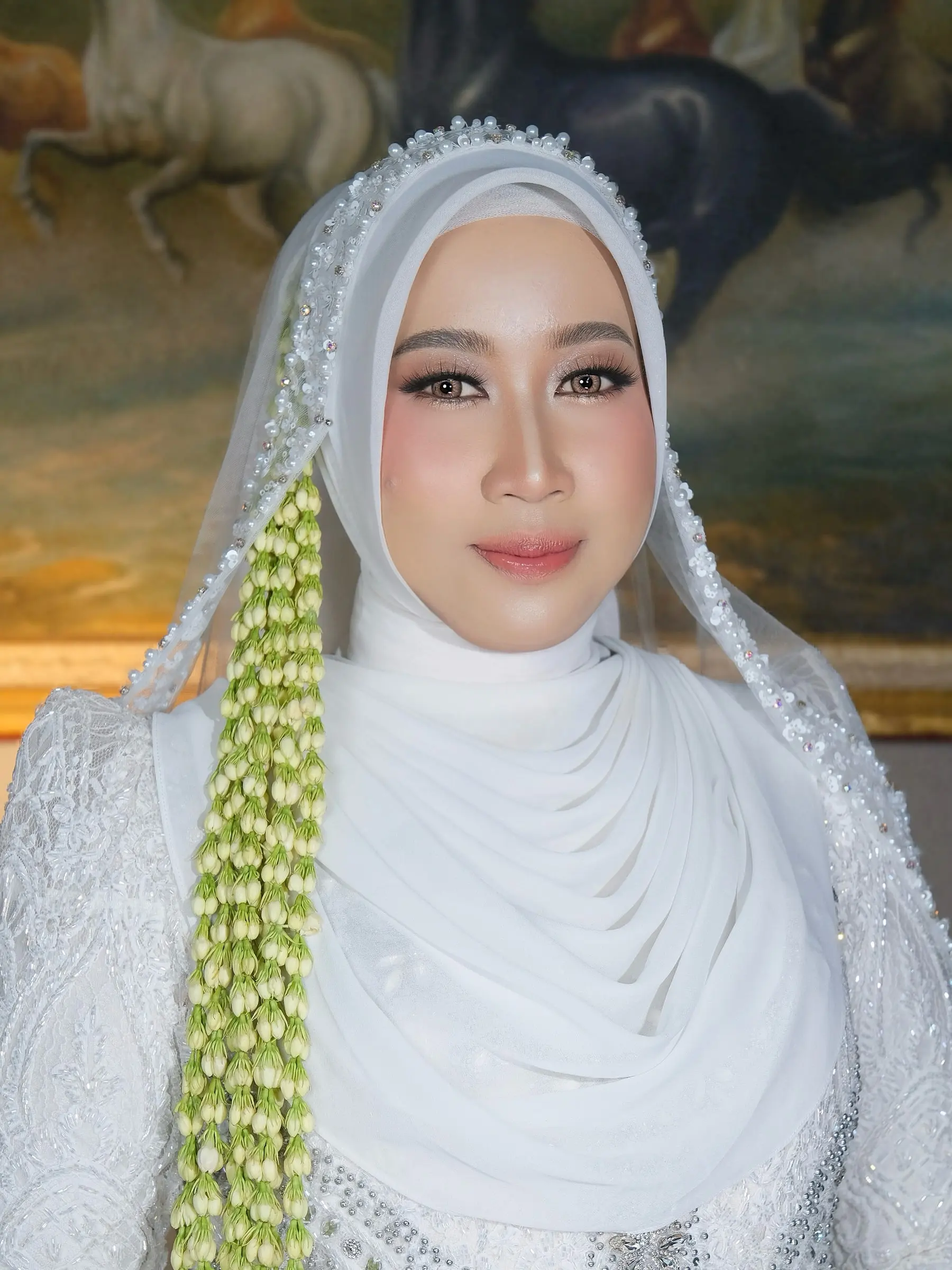 Pengantin berhijab putih dengan kerudung bertabur mutiara dan ronce melati