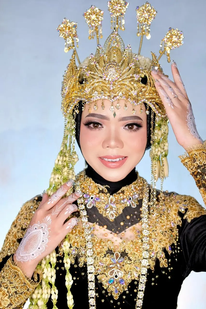 Pengantin berhijab dengan siger emas, ronce melati, dan busana beludru hitam bersulam emas