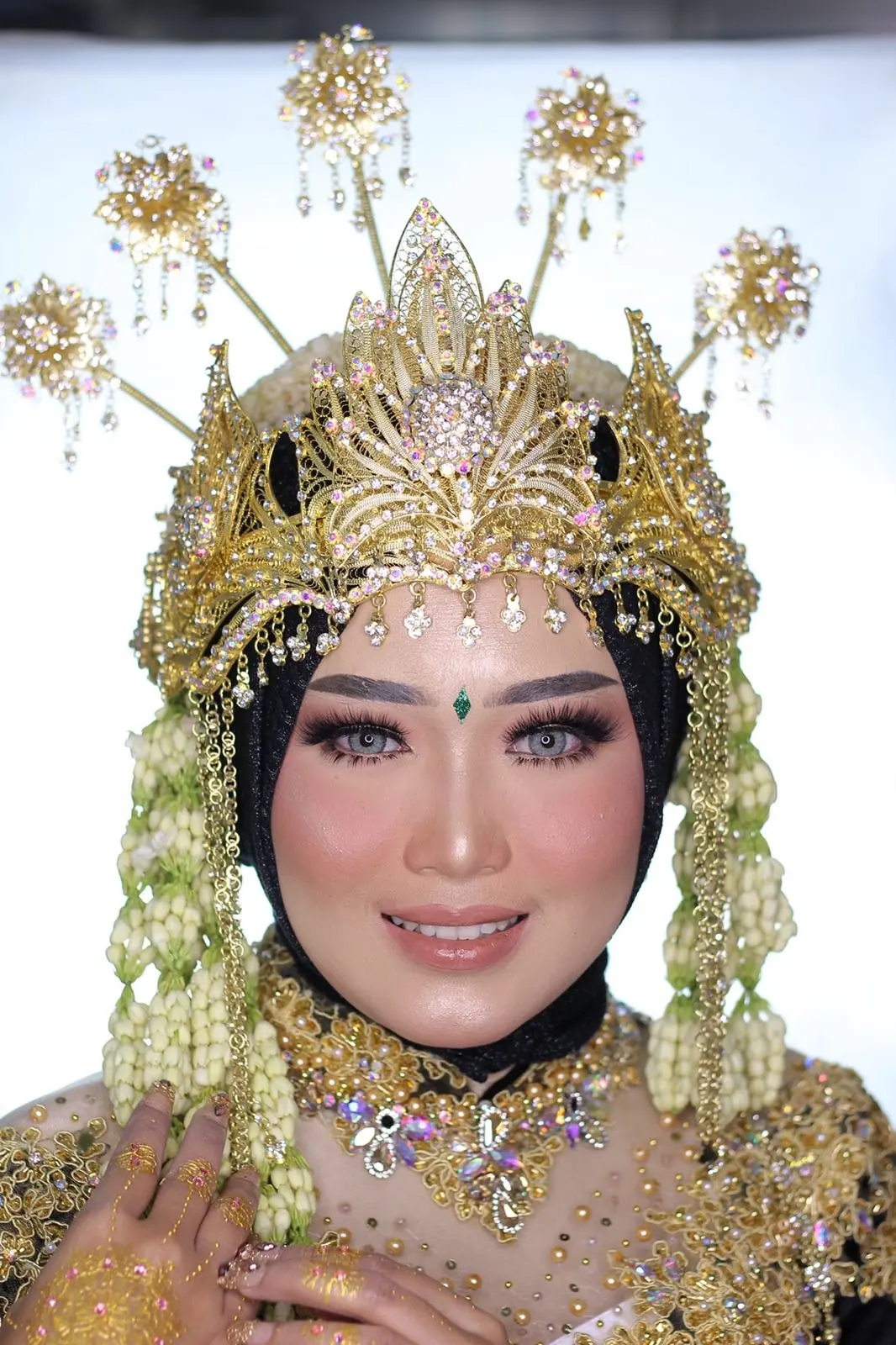 Pengantin berhijab hitam dengan siger Sunda emas dan ronce melati